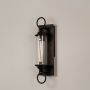 Black metal wall sconce with clear glass tube and ring accents shown on white background for elegant outdoor decor appeal.