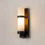 Black metal wall light with glowing frosted glass diffuser shown on white background for indoor home lighting.