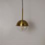 Brass dome pendant lamp with clear glass globe shade shown off on white background for modern home interiors.