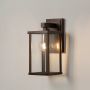 Metal wall lantern glowing softly on white background showcasing warm illumination for stylish outdoor home lighting.